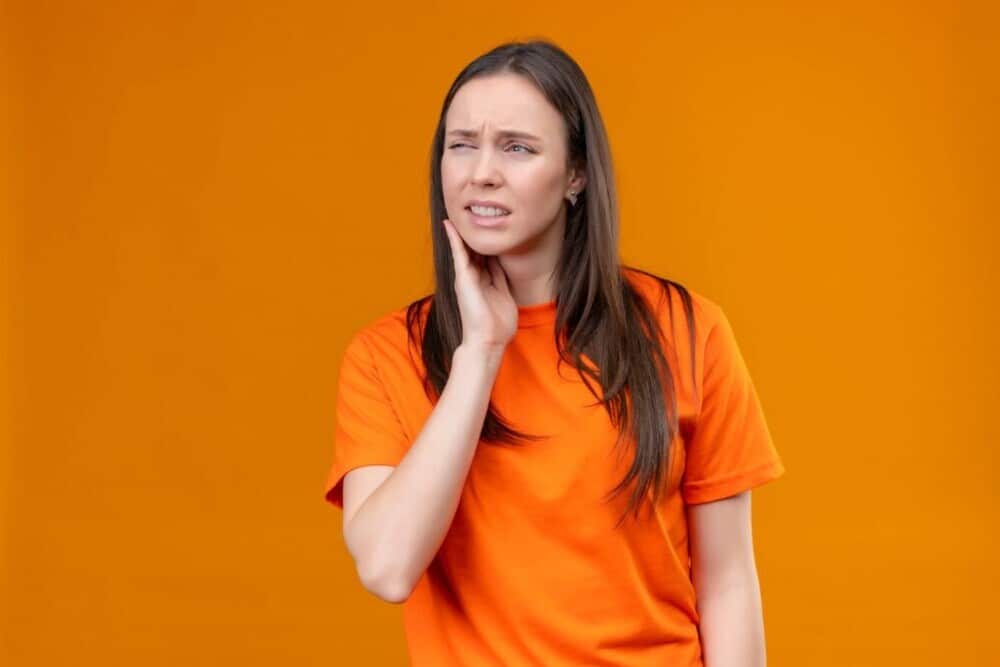 chica vestida de naranja tiene dolor en la atm